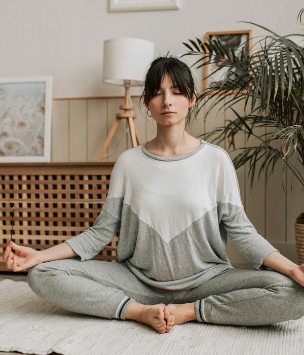Woman in a calming yoga pose, bathed in soft light.
